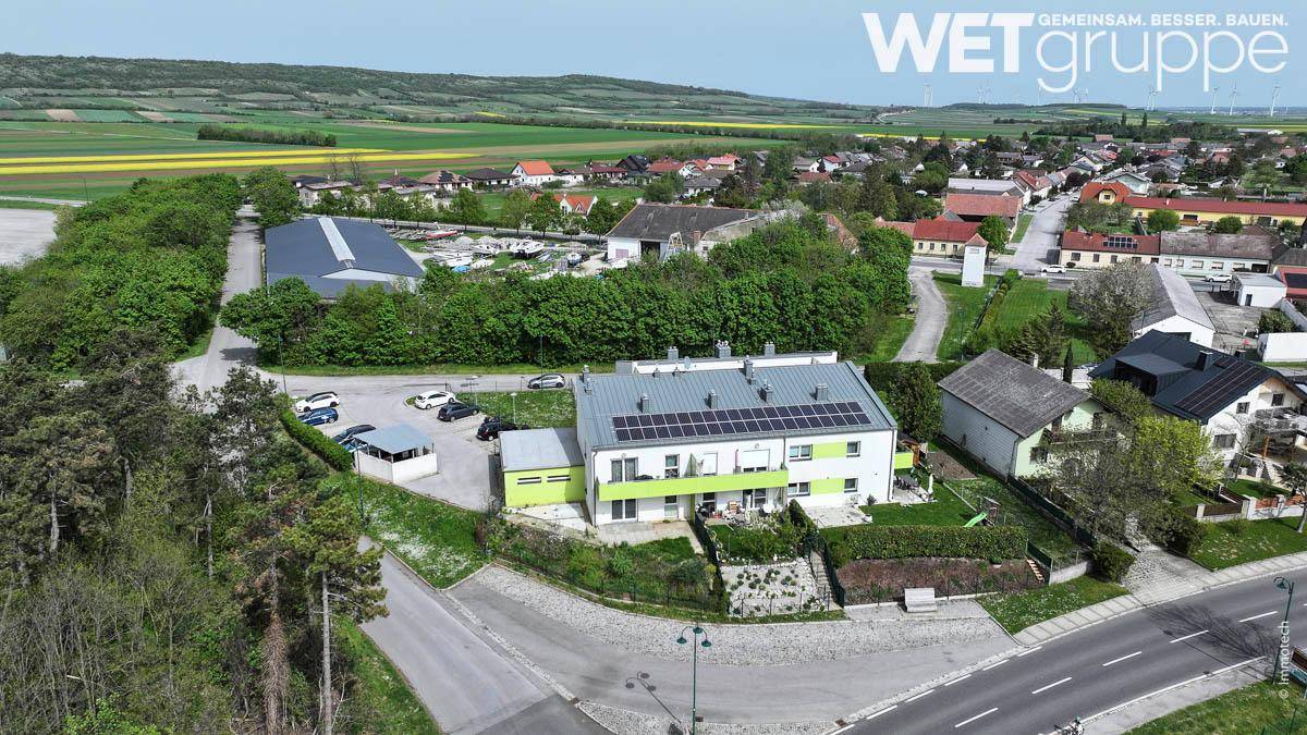 Luftaufnahme eines modernen Wohngebäudes mit Solaranlage, umgeben von grünen Feldern und ländlicher Umgebung.