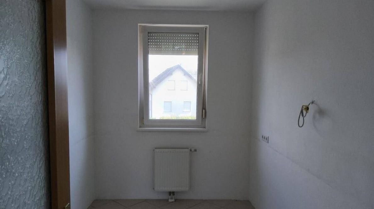 Kleiner Raum mit Fenster, Heizkörper und Fliesenboden, möglicherweise ein Gäste-WC.