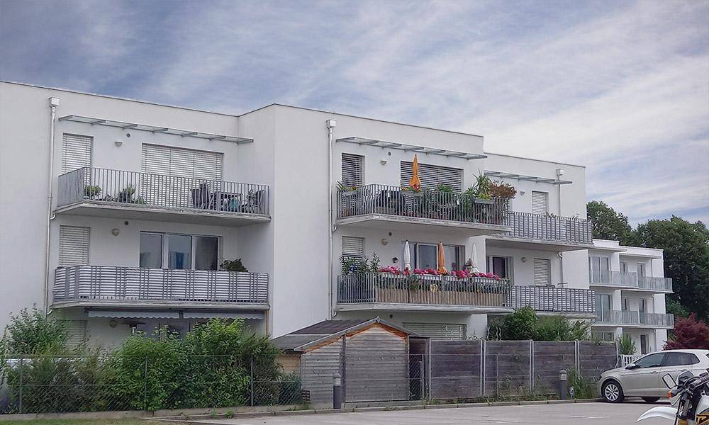 Moderne Wohnanlage mit mehreren Balkonen und gepflegter Außenansicht unter blauem Himmel.