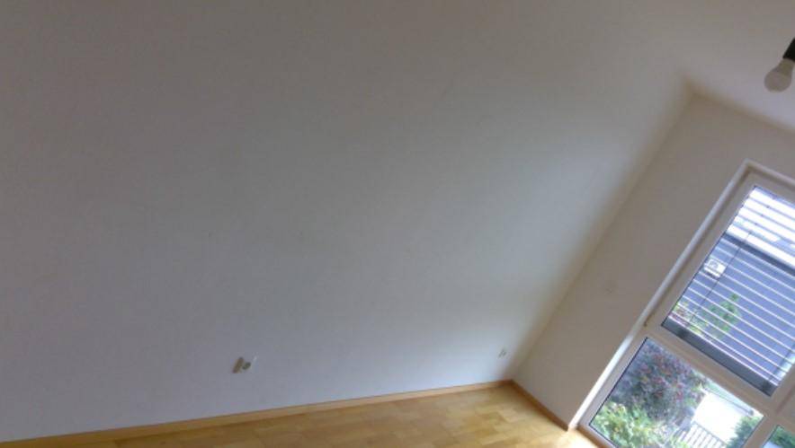 Heller, unmöblierter Raum mit Holzfußboden und großem Fenster, das viel Tageslicht hereinlässt.