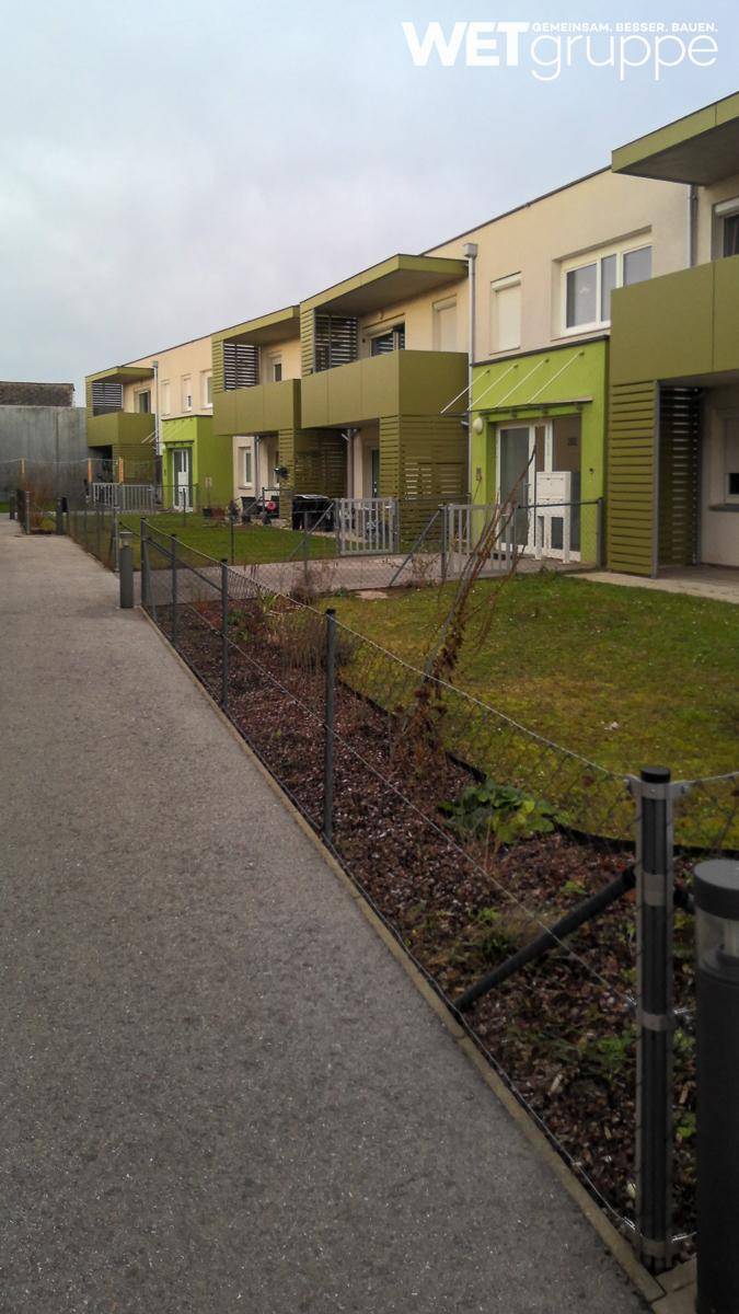 Reihen moderner Wohngebäude mit hellgrünen Akzenten und gepflegten Vorgärten.