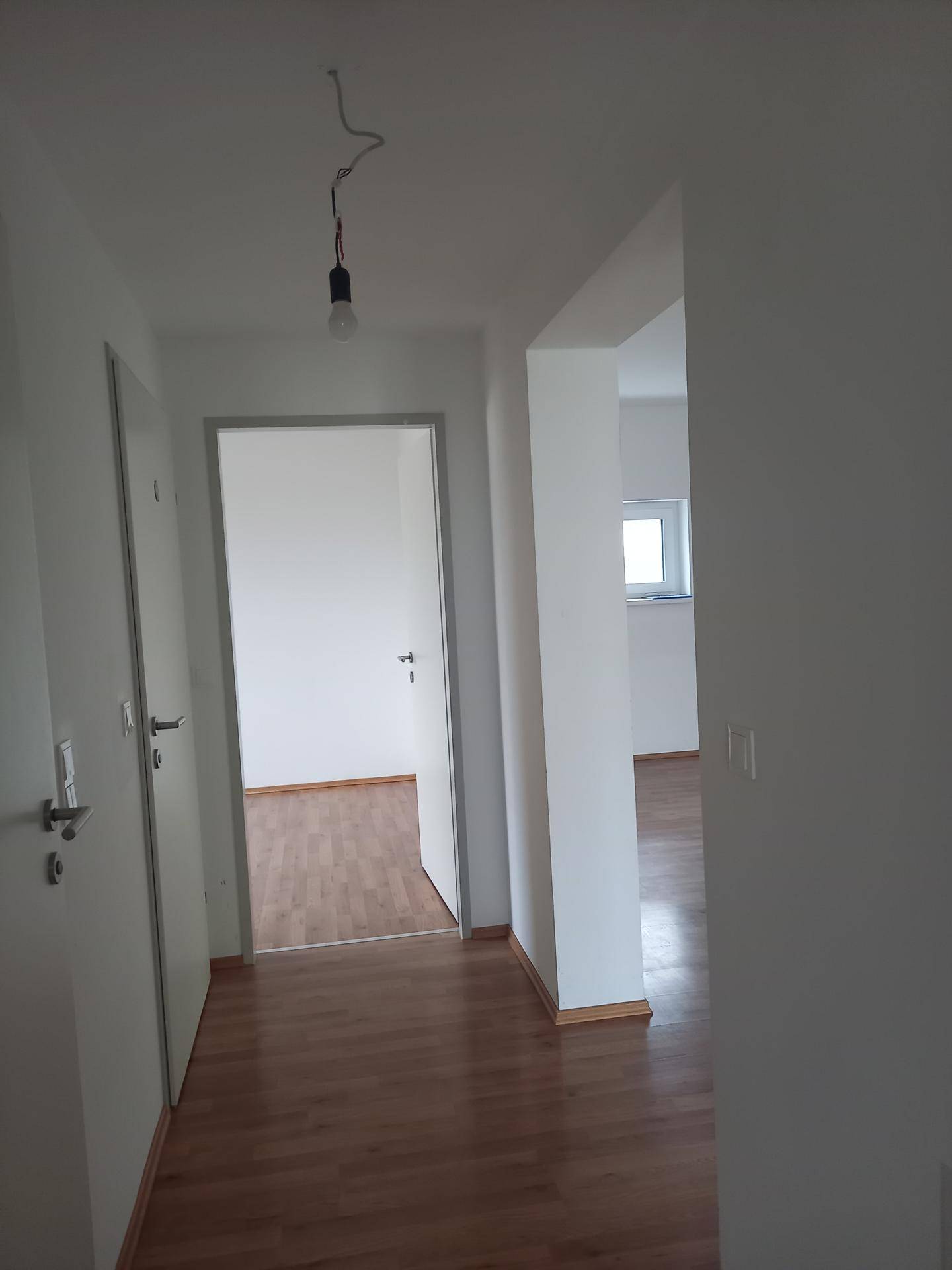 Helle Diele mit Laminatboden und Zugang zu weiteren Räumen in einem gepflegten Zustand.