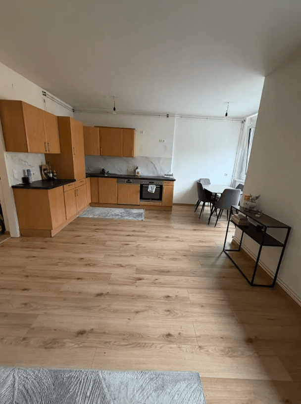Offene Küche mit Holzschränken, Essbereich und hellem Laminatboden, praktisch eingerichtet.