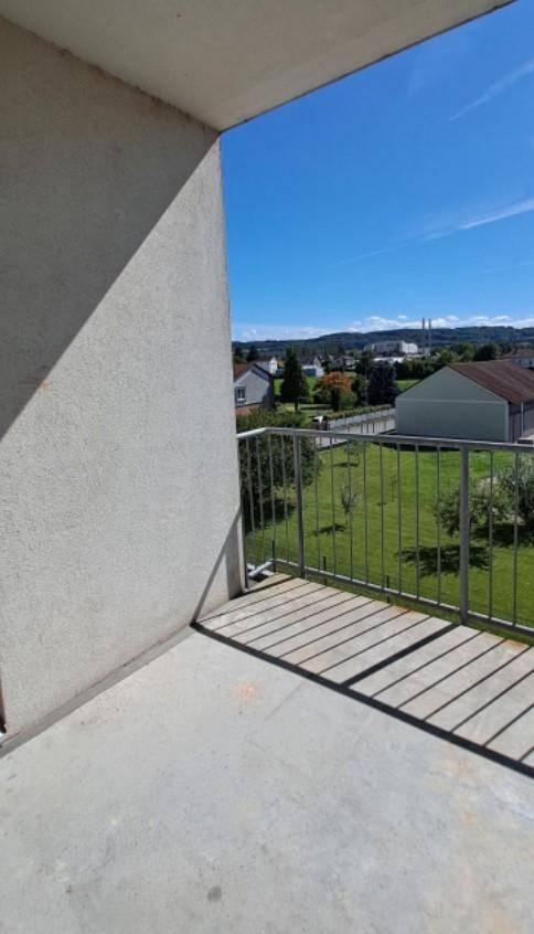 Balkon mit Metallgeländer und weitem Blick über grüne Landschaft und Häuser.