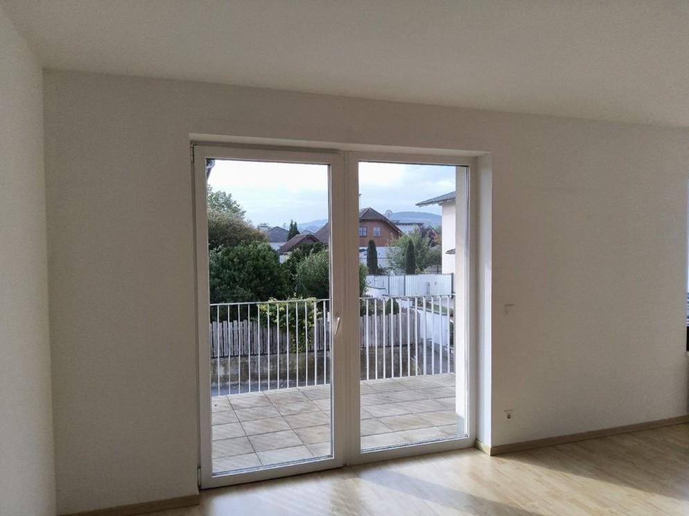 Heller Innenraum mit großem Balkonzugang und Blick auf die umliegende Wohngegend.