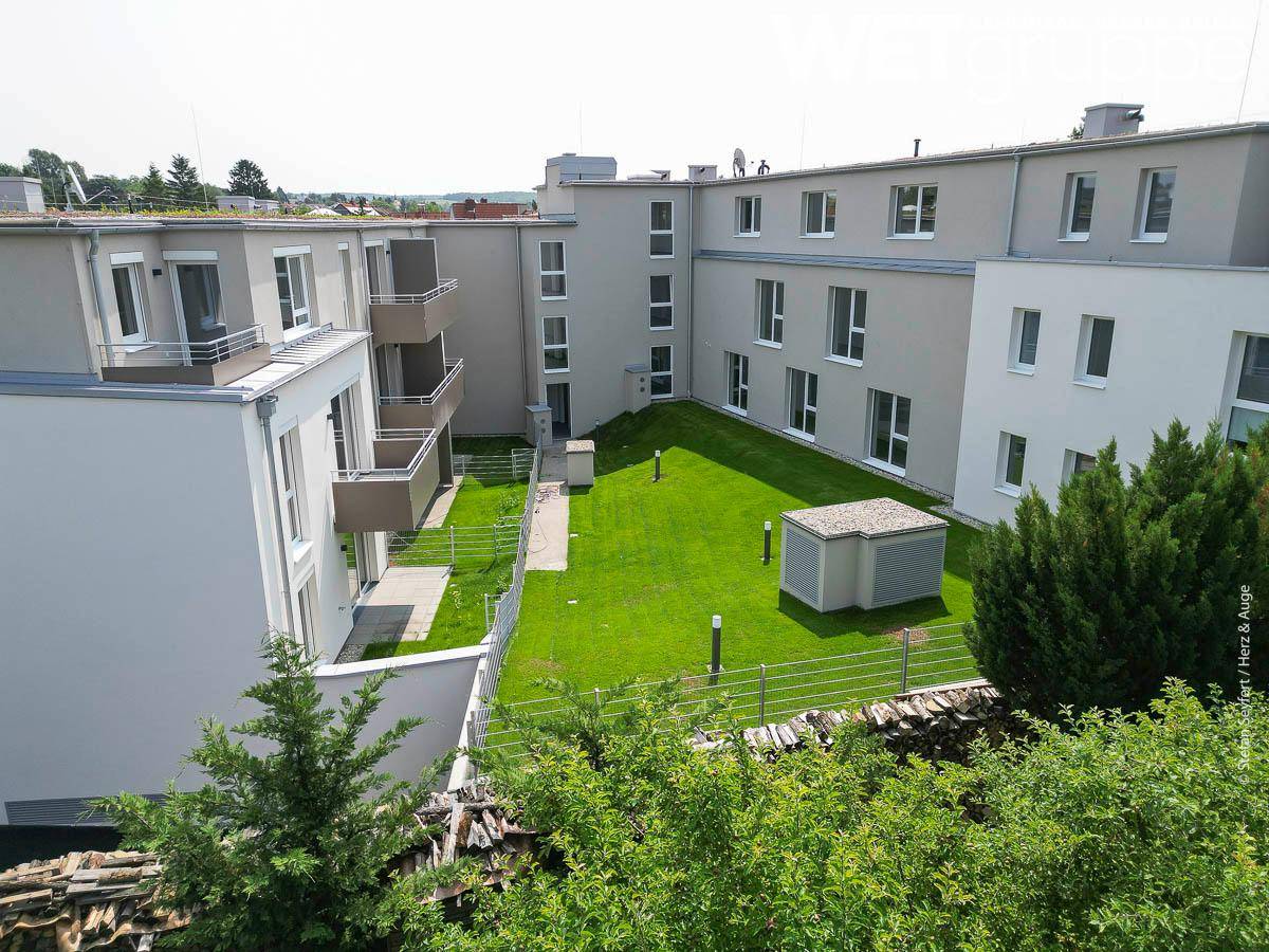 Grüner Innenhof der Wohnanlage mit Rasenflächen und umgebenden Gebäudefassaden.