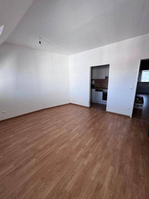 Heller Wohnbereich mit Laminatboden und Zugang zu einer kleinen Küchenzeile.