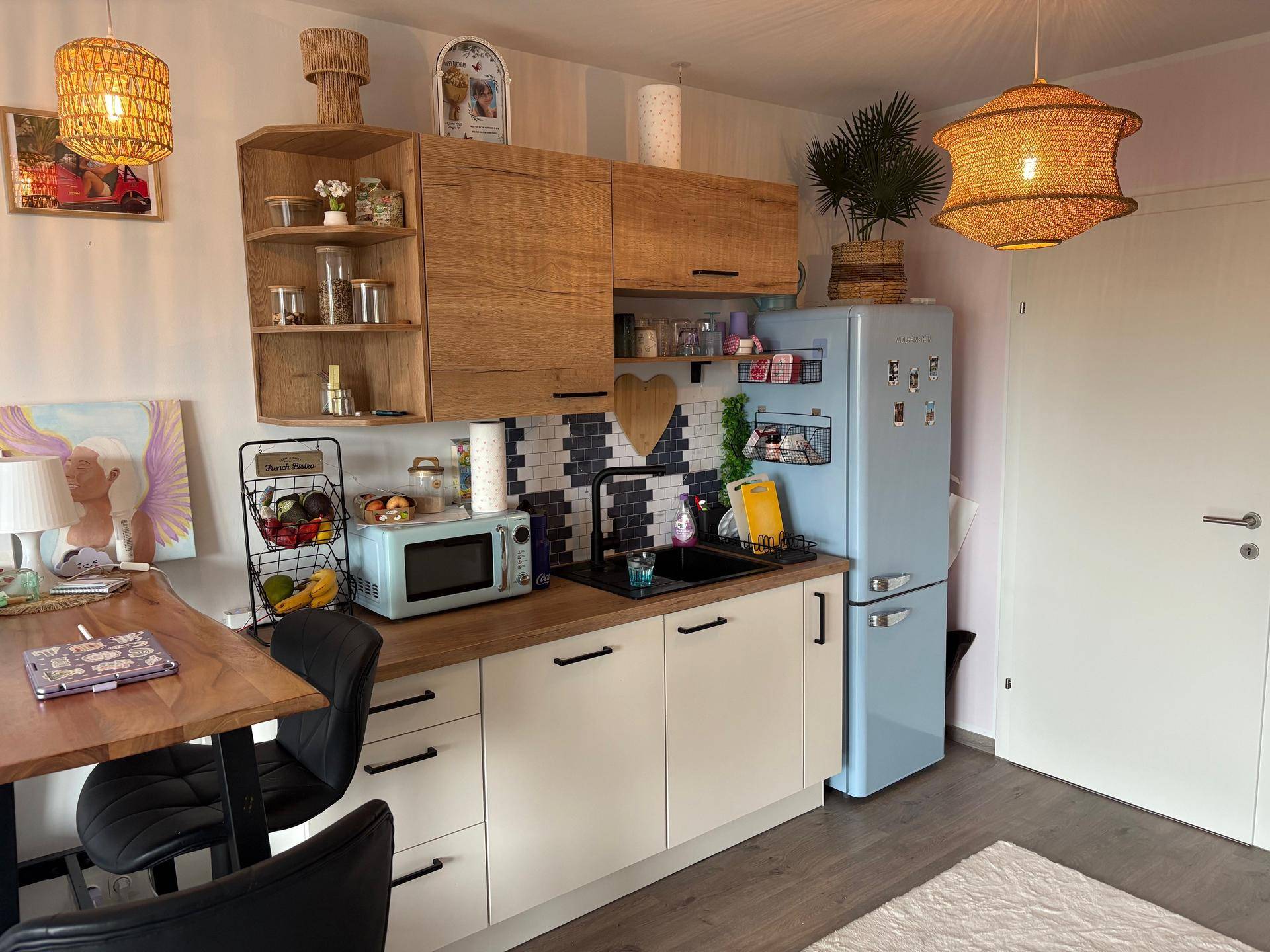 Moderne Küche mit hellen Holzschränken, weißer Arbeitsplatte und einem auffälligen blauen Kühlschrank.