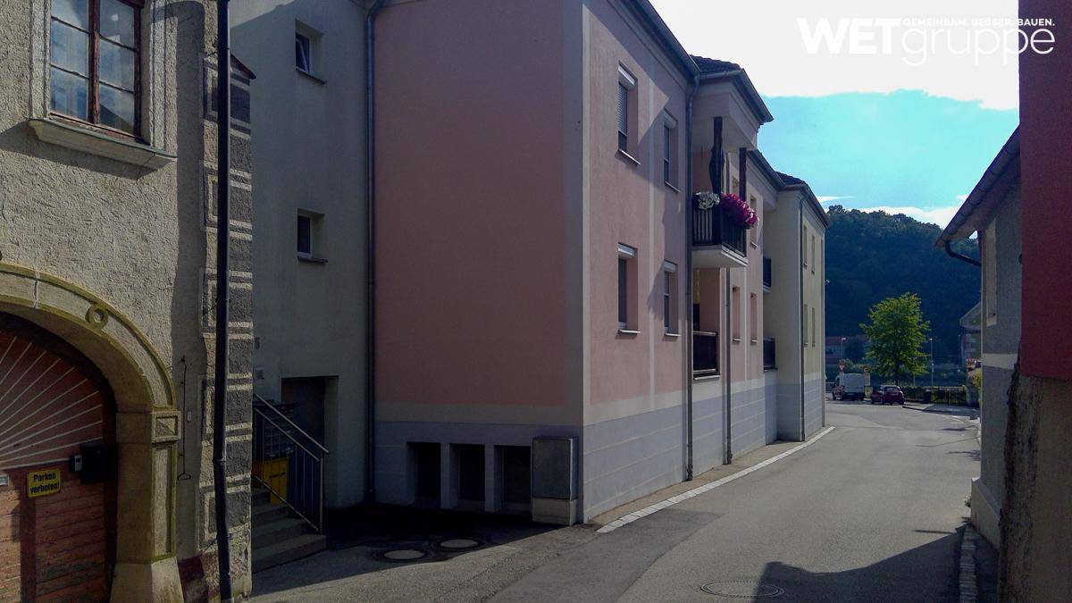 Seitenansicht eines Mehrfamilienhauses an einer Straße mit Balkonen und gepflegter Fassade.