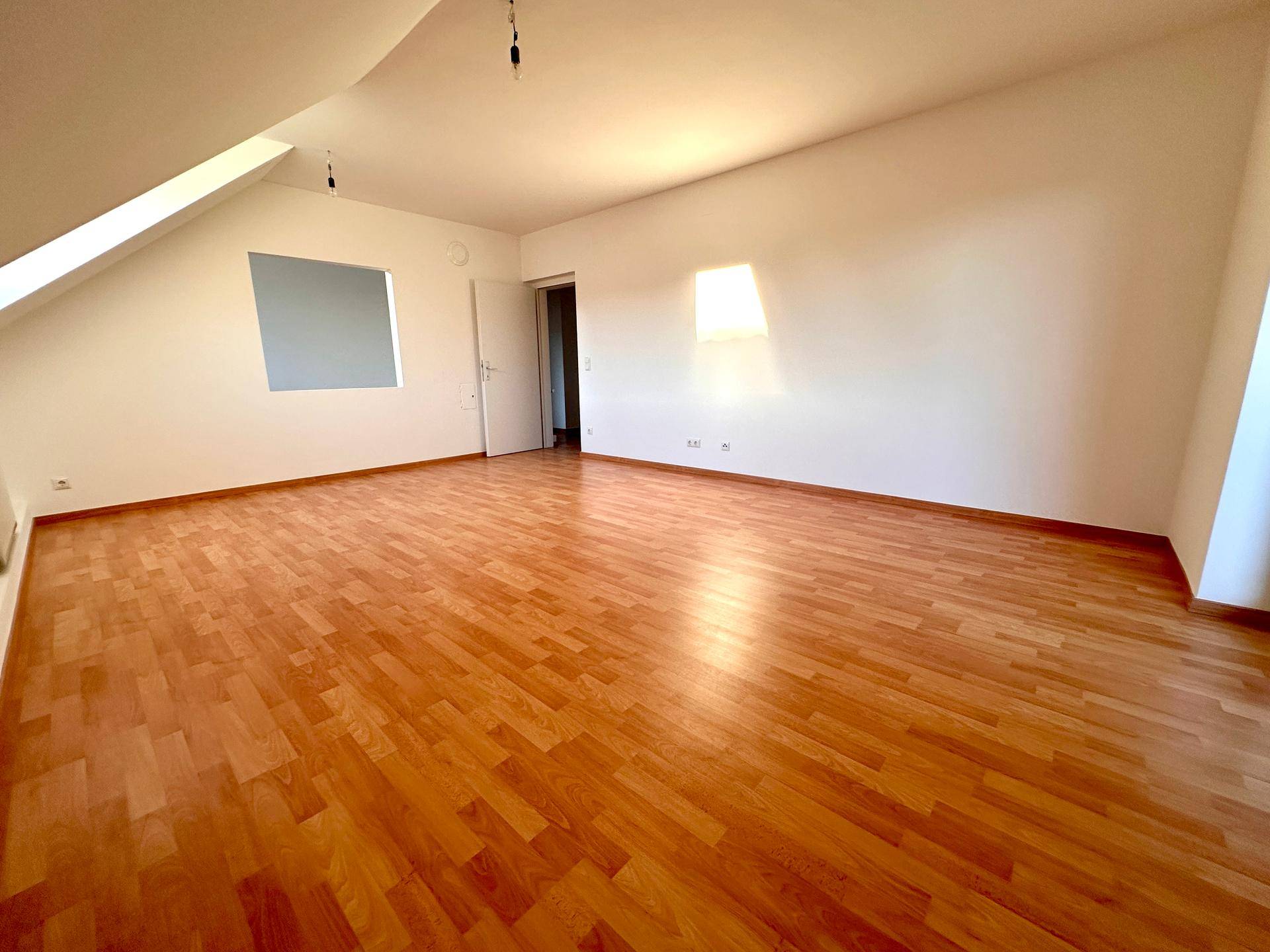 Großer, heller Wohnraum mit Laminatboden und viel Tageslicht, bietet eine angenehme Atmosphäre.