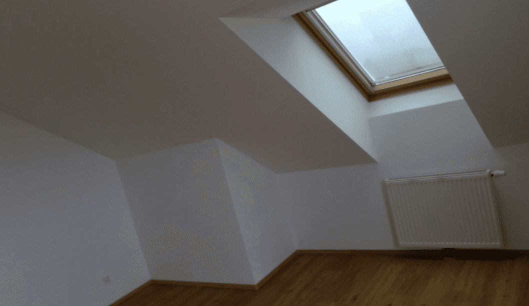 Heller Dachraum mit Dachfenster, Holzboden und Heizkörper, ideal für individuelle Nutzung.