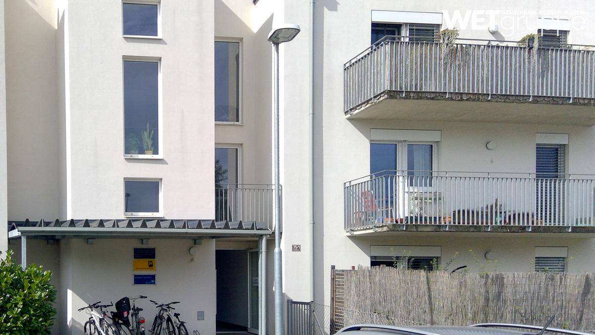 Moderne Fassade eines Mehrfamilienhauses mit Balkonen und großen Fenstern.