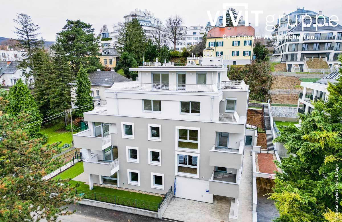 Moderne Wohnanlage eingebettet in eine grüne Umgebung mit weiteren Gebäuden.
