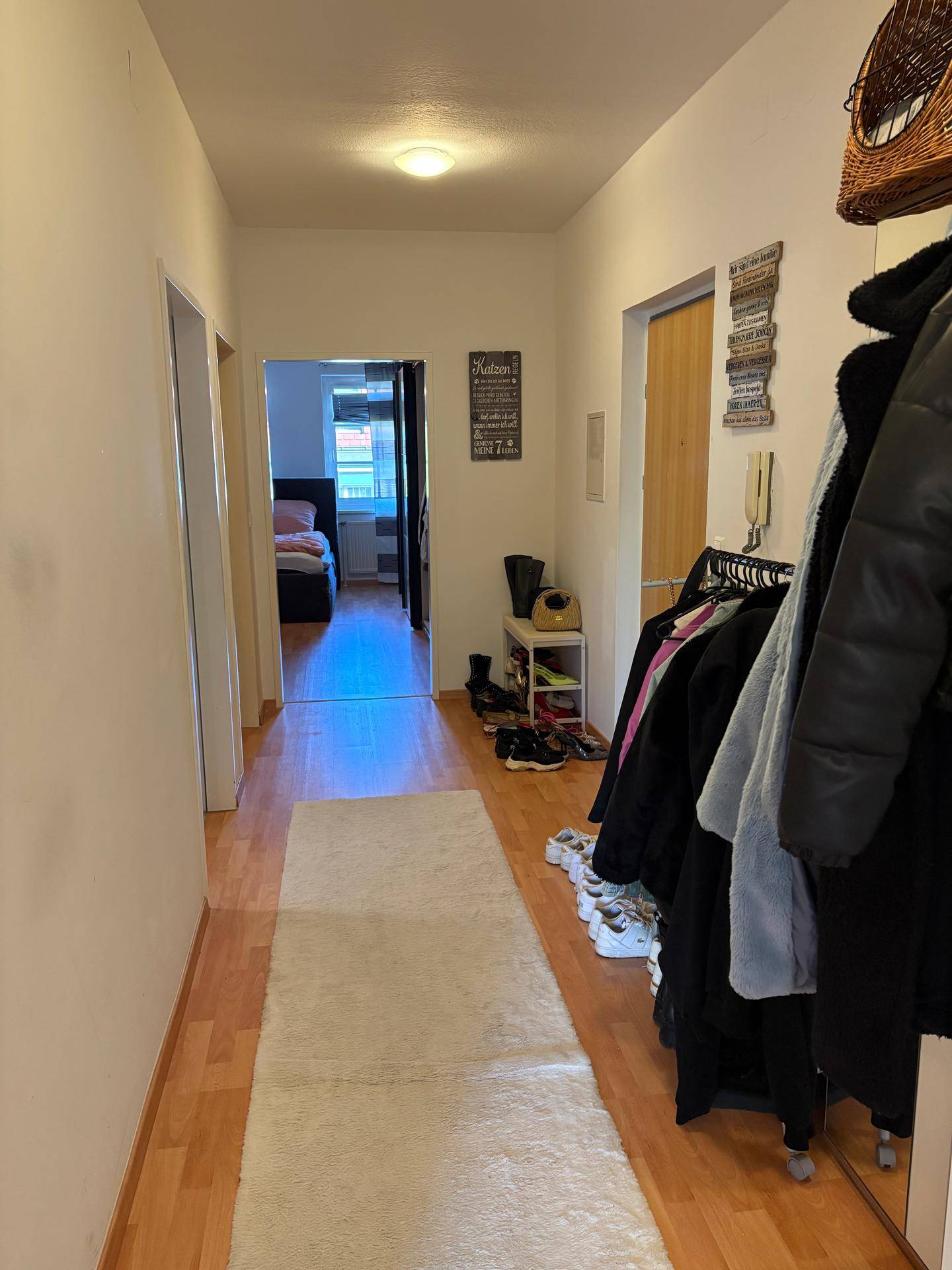 Langer Flur mit Laminatboden, Garderobe und Blick in ein Schlafzimmer.