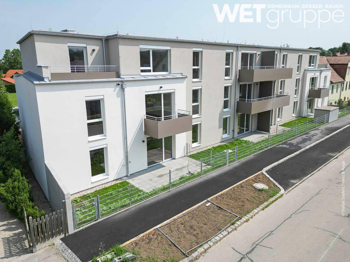 Ansicht der modernen Wohnanlage mit Balkonen und ebenerdigen Terrassenbereichen.