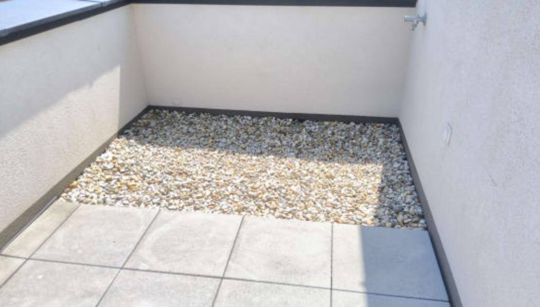 Kleine Terrasse mit Fliesen und Zierkies, ideal für eine gemütliche Sitzecke im Freien.