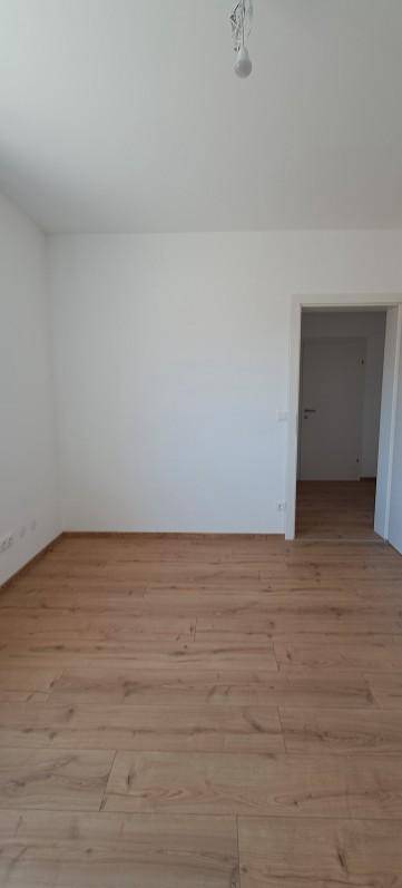 Geräumiges, leeres Zimmer mit Holzboden und weiß gestrichenen Wänden, ideal für neue Einrichtung.
