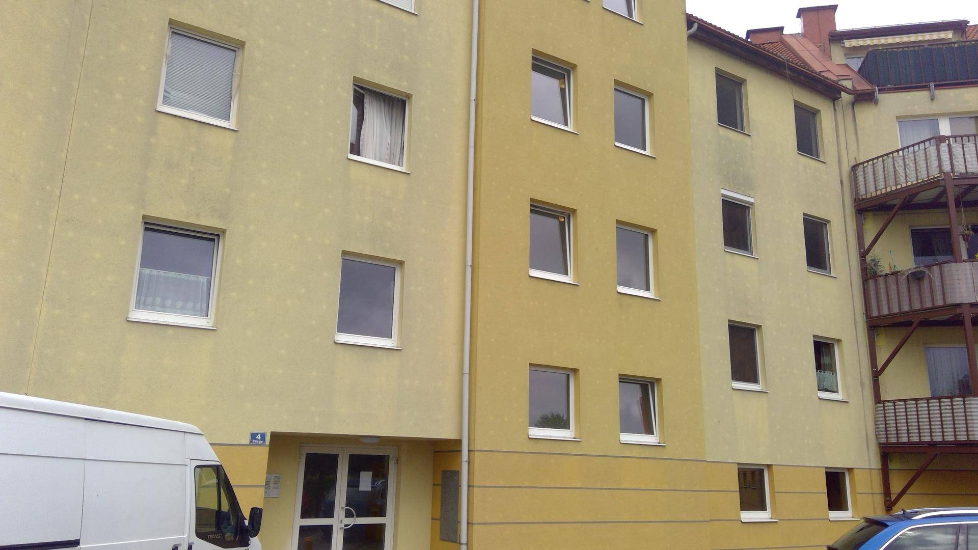 Vorderansicht des Mehrfamilienhauses mit gelber Fassade und Eingangsbereich.