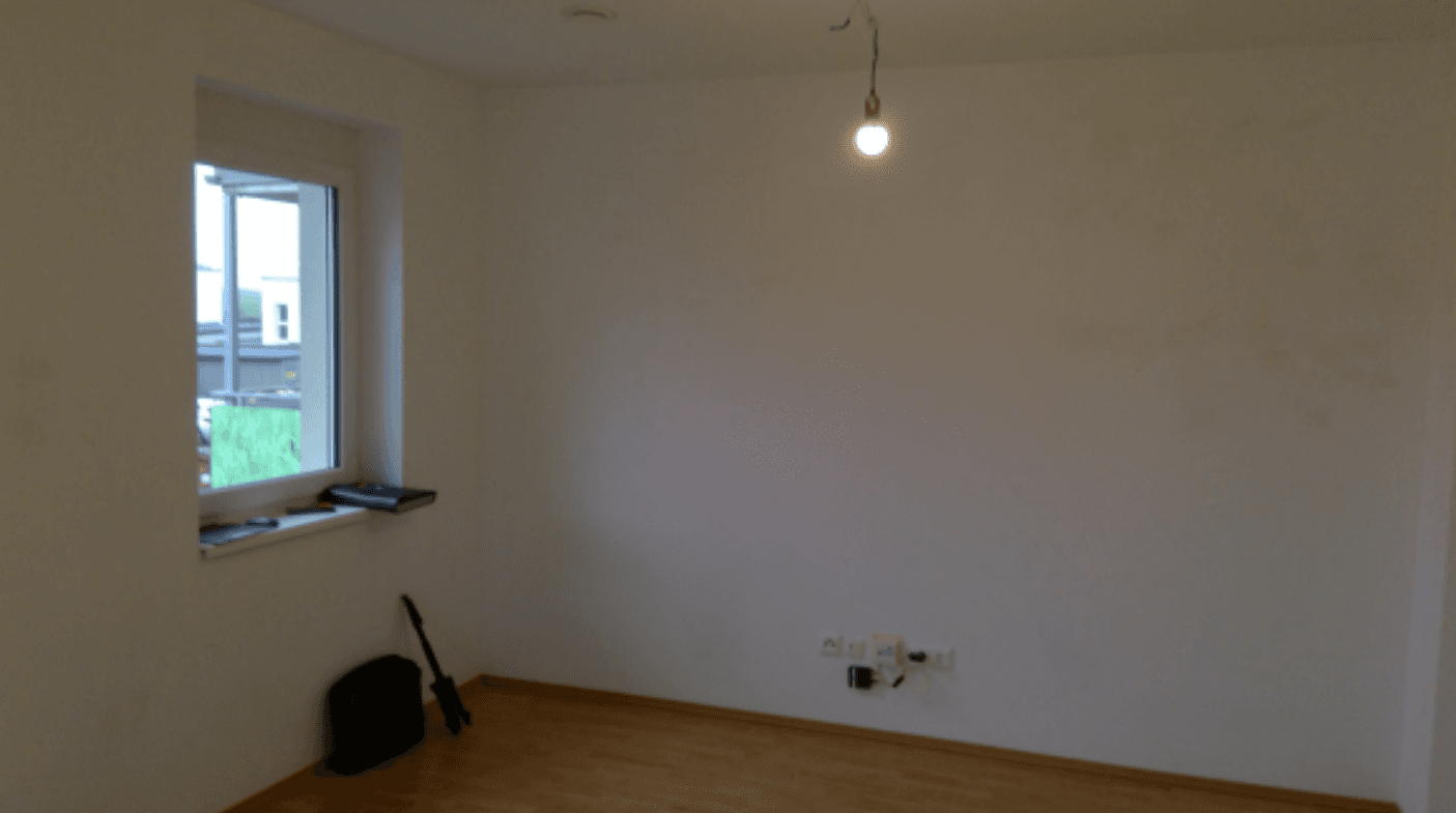 Leerer Raum mit weißen Wänden, einem Fenster und hellem Laminatboden, bereit zur individuellen Gestaltung.