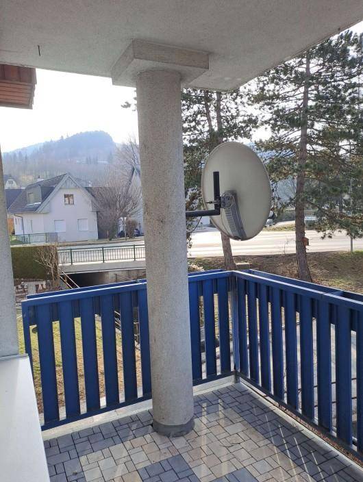 Balkon mit blauer Brüstung, Satellitenschüssel und weitem Blick auf die umliegende Berglandschaft.