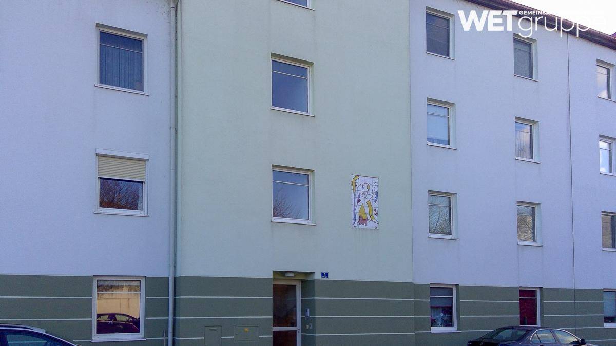 Mehrfamilienhaus mit schlichter Fassade und mehreren Fenstern.