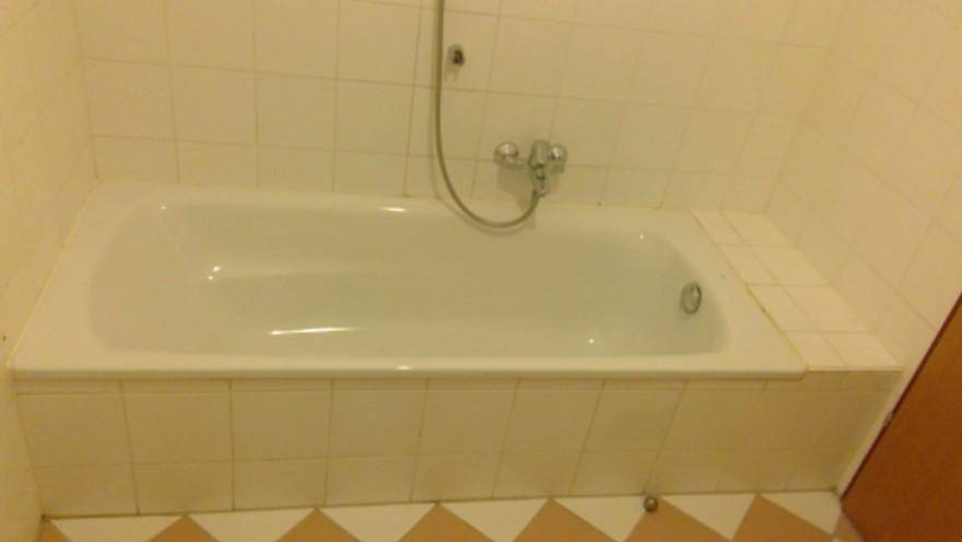 Badezimmer mit eingebauter Badewanne und weißen Fliesen, bereit zur Modernisierung.