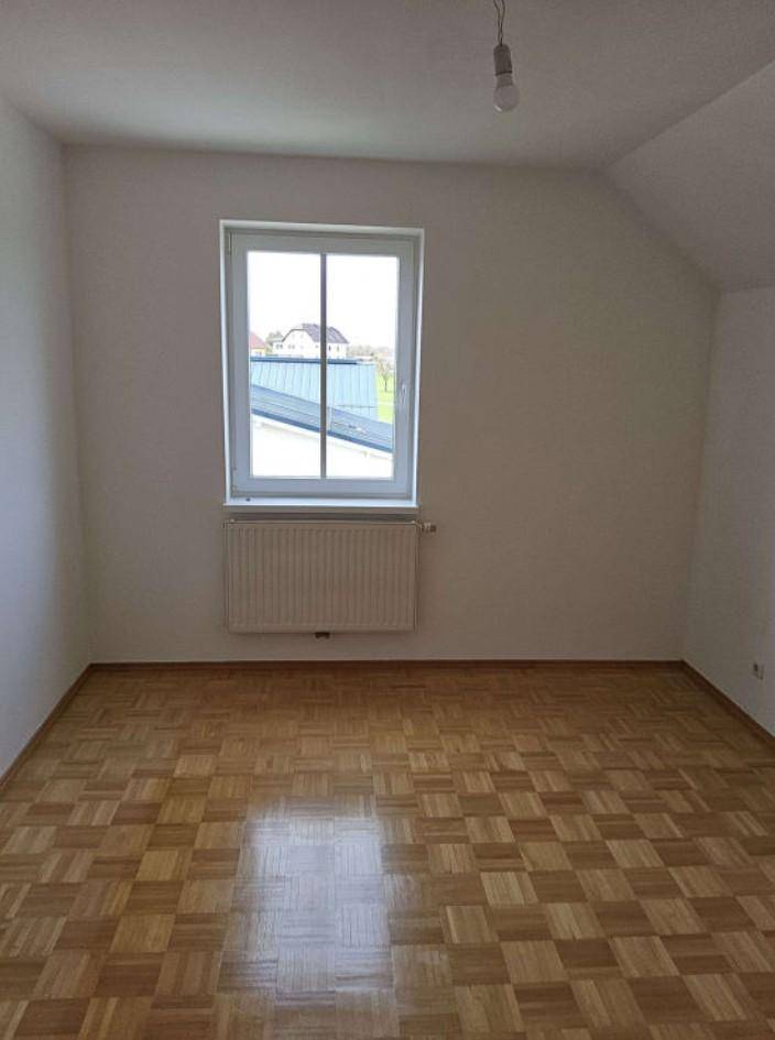 Helles Zimmer mit Parkettboden, Fenster und Blick über die Dächer, ideal als Schlafzimmer.