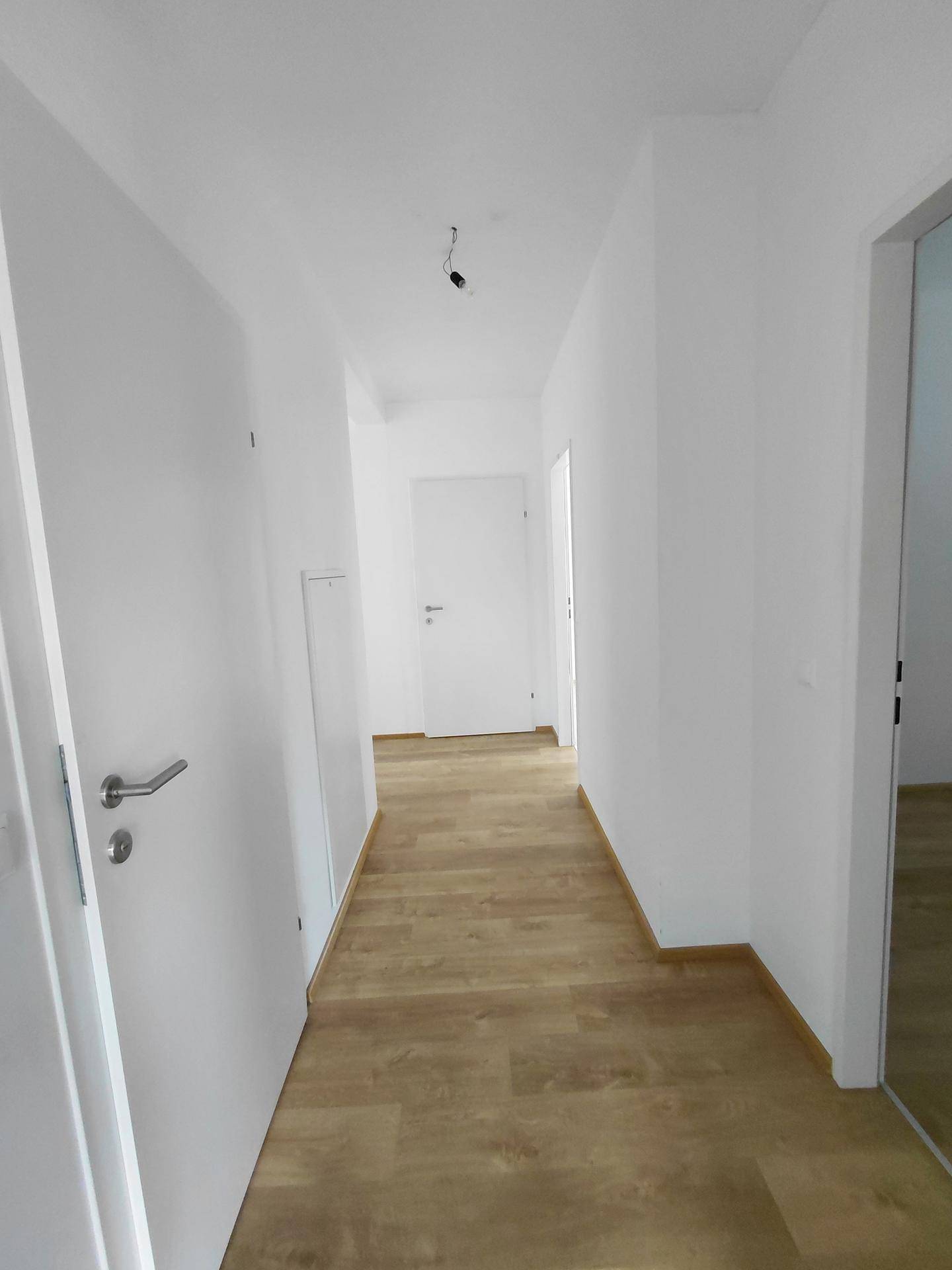 Heller Flur mit Laminatboden und mehreren Türen zu den Zimmern.