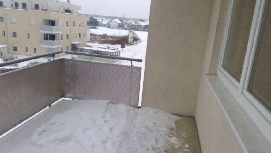 Balkon mit Schnee bedeckt, bietet einen Blick auf die umliegenden Gebäude und die verschneite Landschaft.