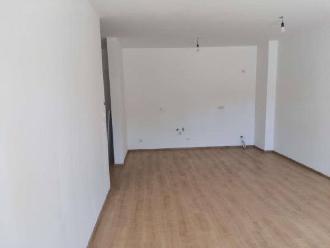 Leerer Raum mit hellem Laminatboden und weißen Wänden, bereit für die individuelle Gestaltung.