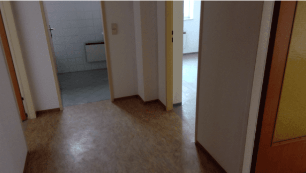 Heller Flur mit gemustertem Bodenbelag und Zugang zu verschiedenen Räumen, inklusive Badezimmer.