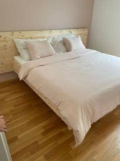 Helles Schlafzimmer mit Holzbettgestell und Parkettboden, ideal für eine ruhige Nachtruhe.