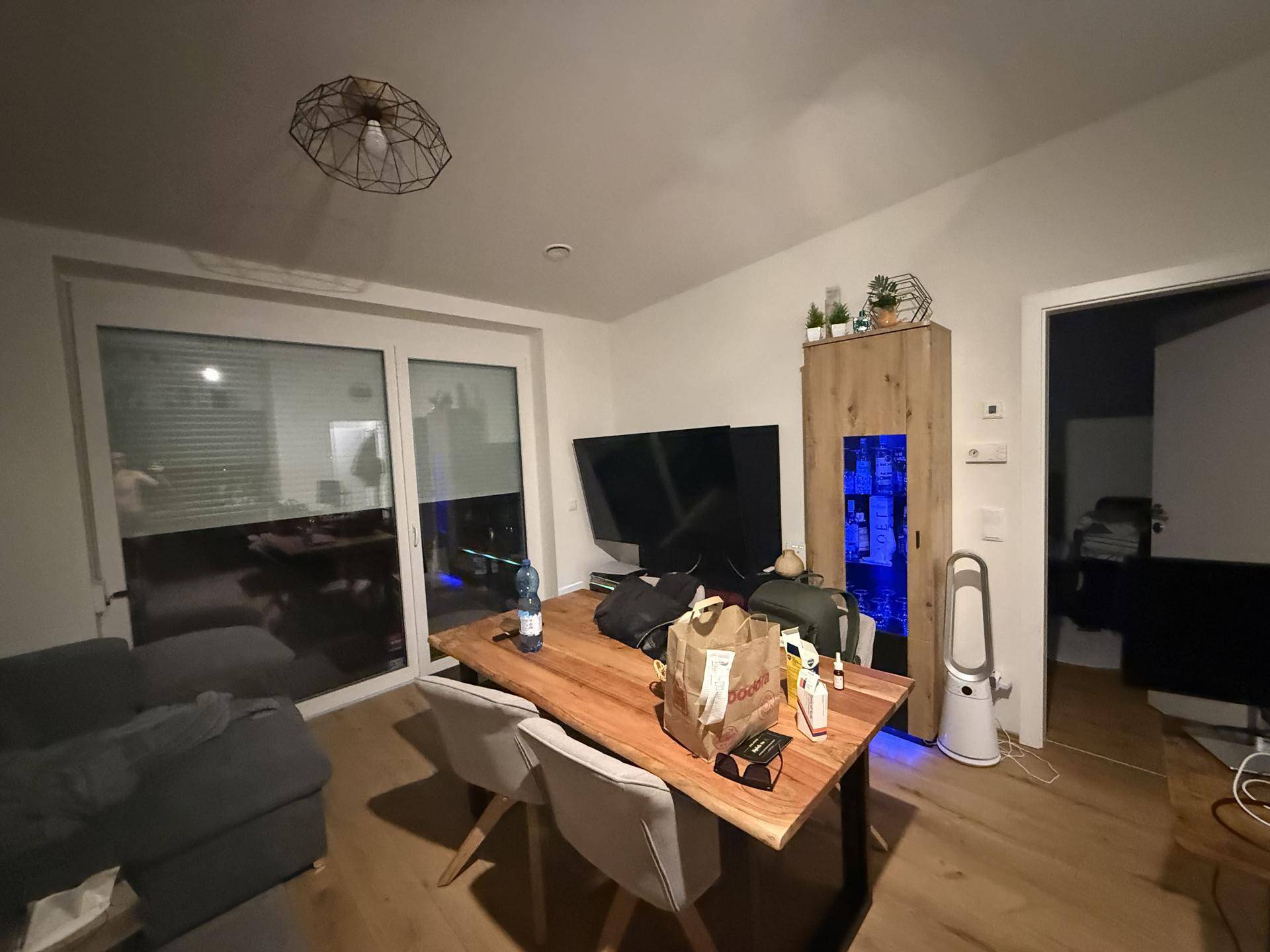 Essbereich mit rustikalem Holztisch, bequemen Stühlen und großzügiger Schiebetür zum Außenbereich.