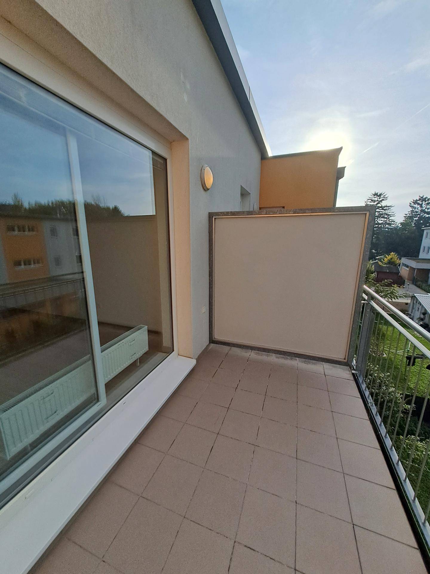 Heller Balkon mit Fliesenboden und Metallgeländer, ideal für entspannte Stunden im Freien.