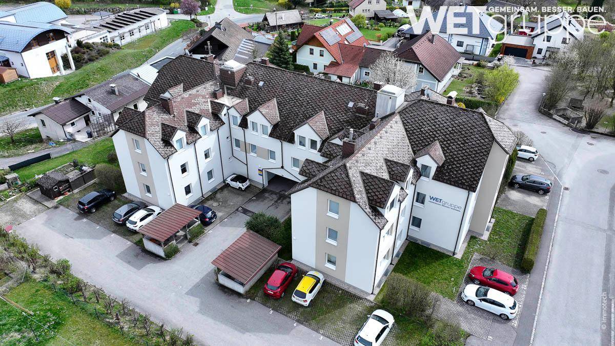 Luftaufnahme des Wohngebäudes mit Parkplätzen und der umliegenden Wohnsiedlung.