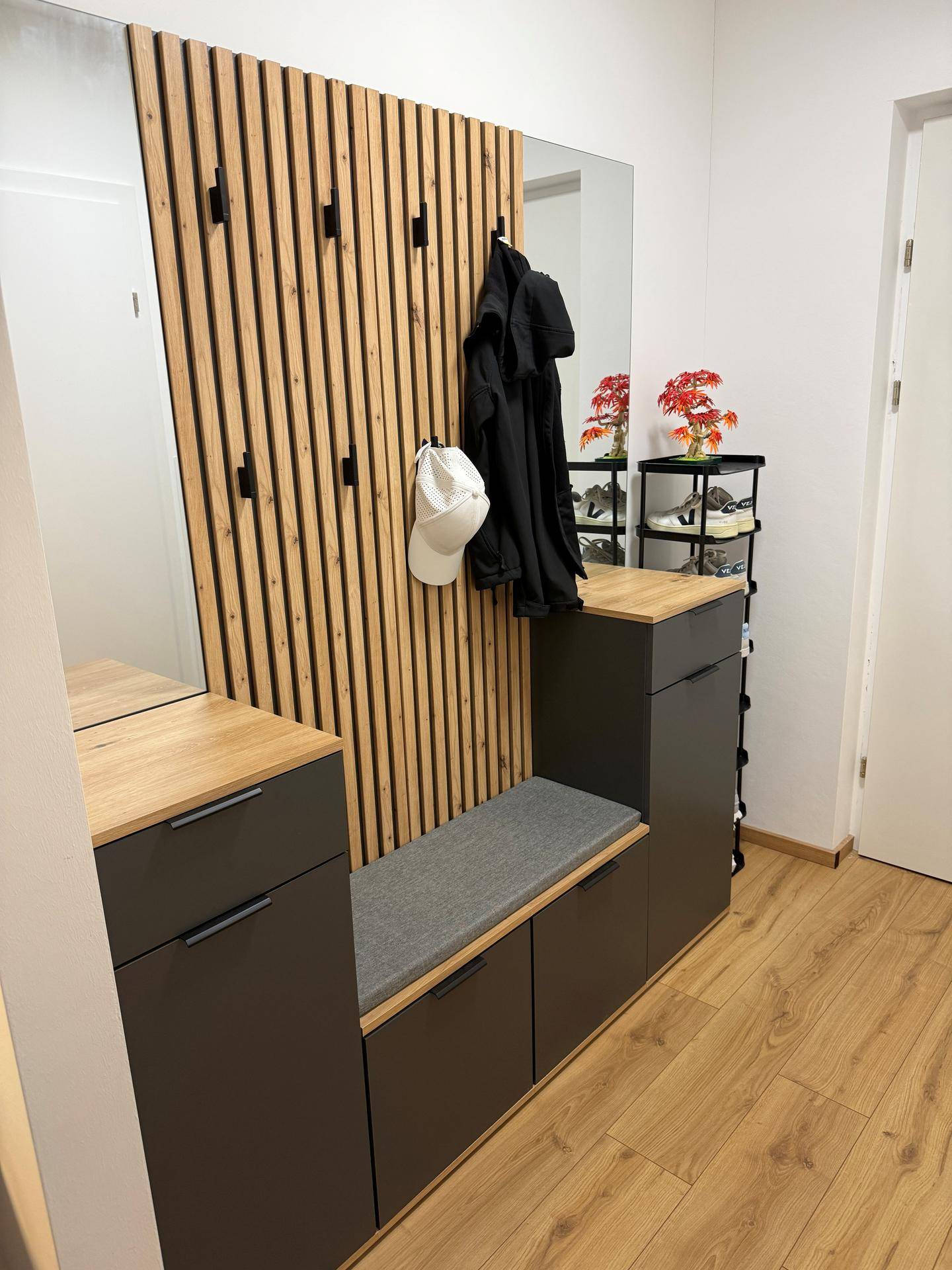 Moderner Eingangsbereich mit Garderobe, Sitzbank, Spiegel und Schuhregal.