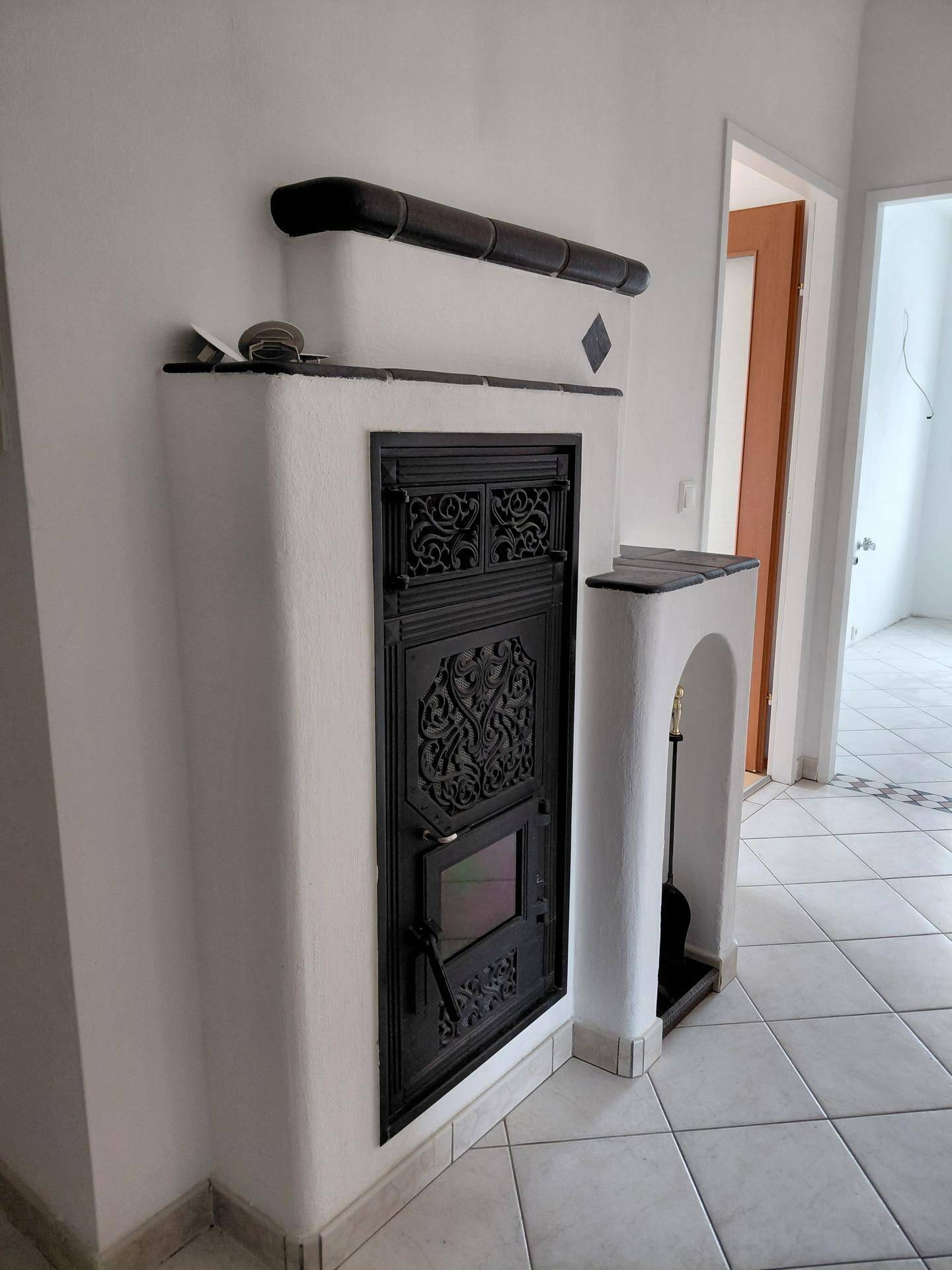 Detailansicht eines traditionellen Kachelofens mit kunstvollen Verzierungen im Flurbereich.