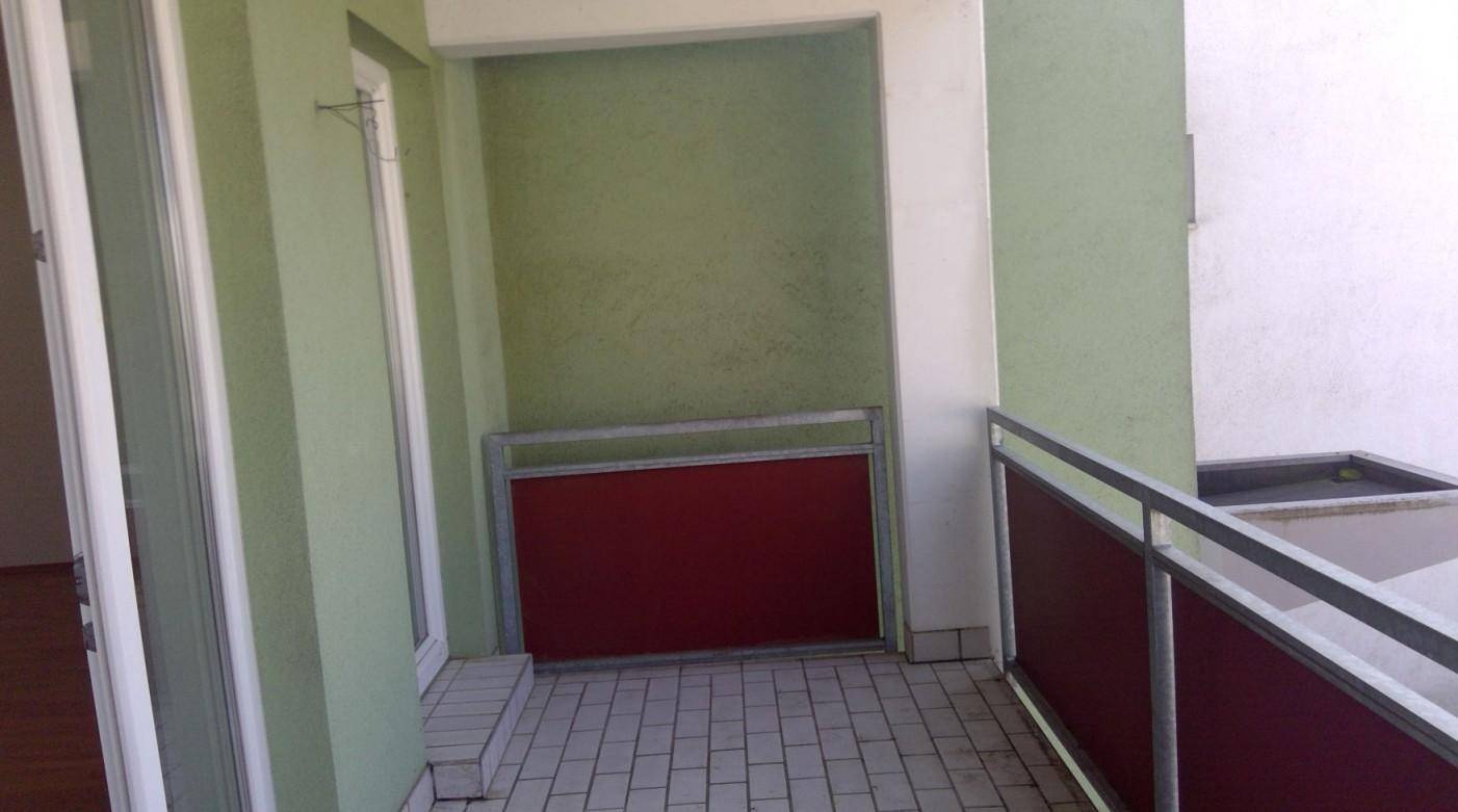 Geräumiger Balkon mit grünen Wänden und roten Akzenten, ideal für Entspannung im Freien.