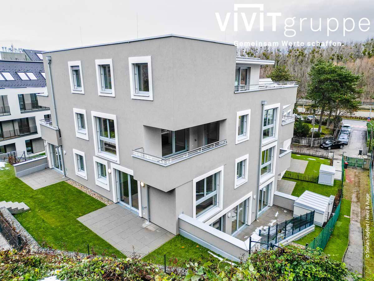 Moderne Wohnanlage mit heller Fassade, großen Fenstern und gepflegten Grünflächen.