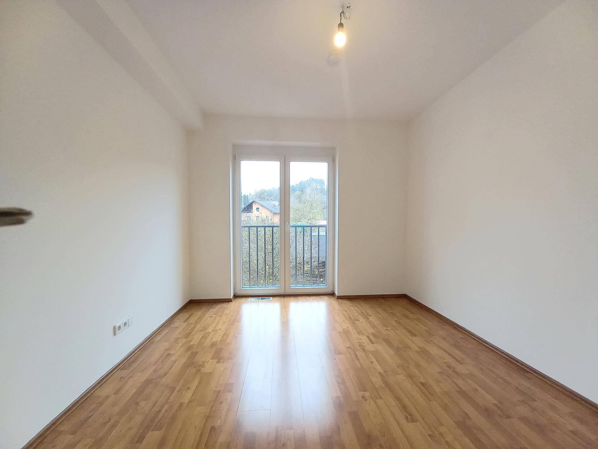 Freundliches Zimmer mit Laminatboden und einem französischen Balkon, bietet viel Tageslicht und Ausblick.