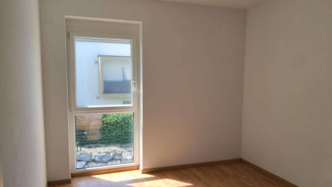 Freundliches Zimmer mit Holzboden und Fenster zum Gartenbereich, ideal als Schlaf- oder Arbeitszimmer.