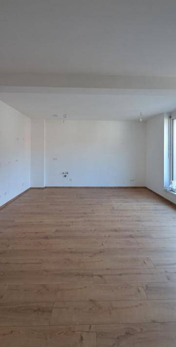 Großes, helles Zimmer mit Holzboden und Fenster, bietet viel Platz für individuelle Gestaltung.