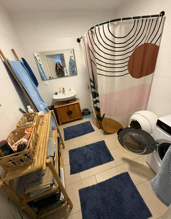 Badezimmer mit Dusche, Einzelwaschbecken und Waschmaschine.