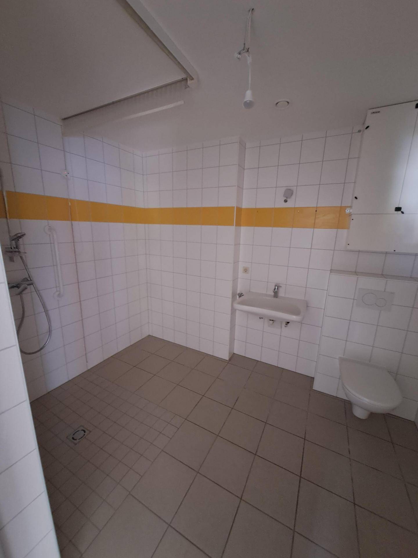 Barrierefreies Badezimmer mit Dusche, WC, Waschbecken und Haltegriffen für mehr Sicherheit.