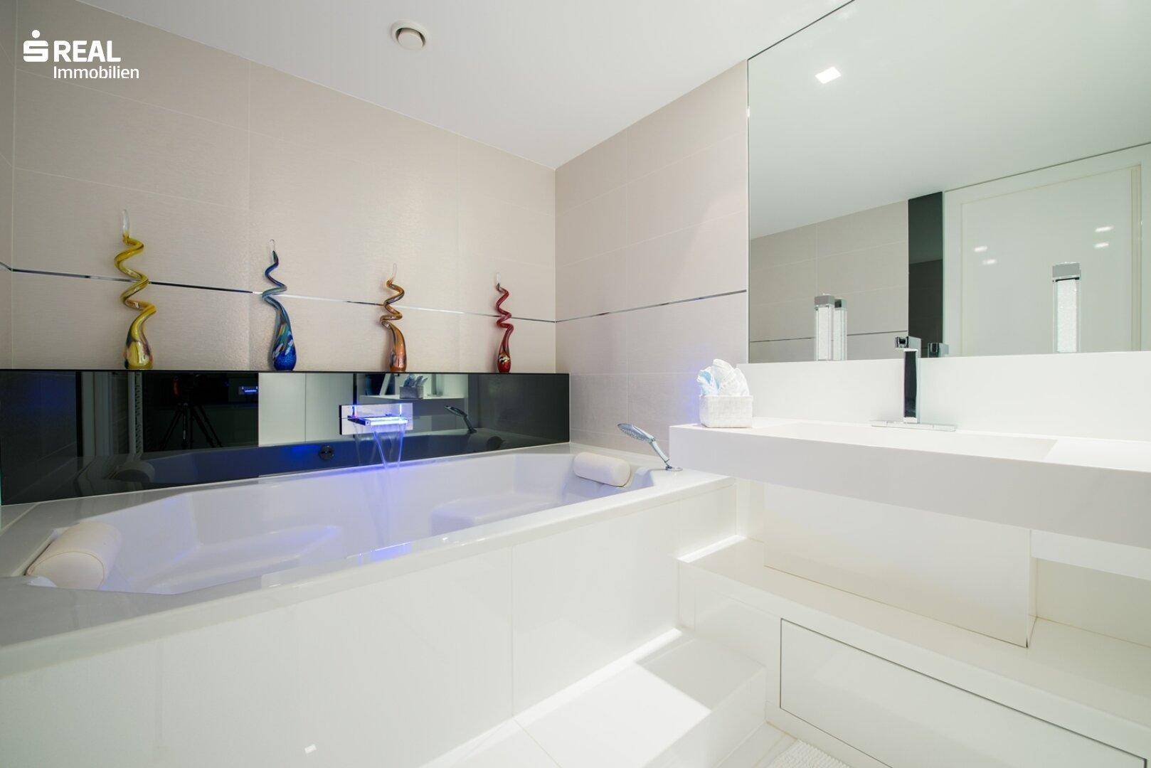 Modernes Badezimmer mit großer Badewanne, eleganten Fliesen und stilvoller Beleuchtung.