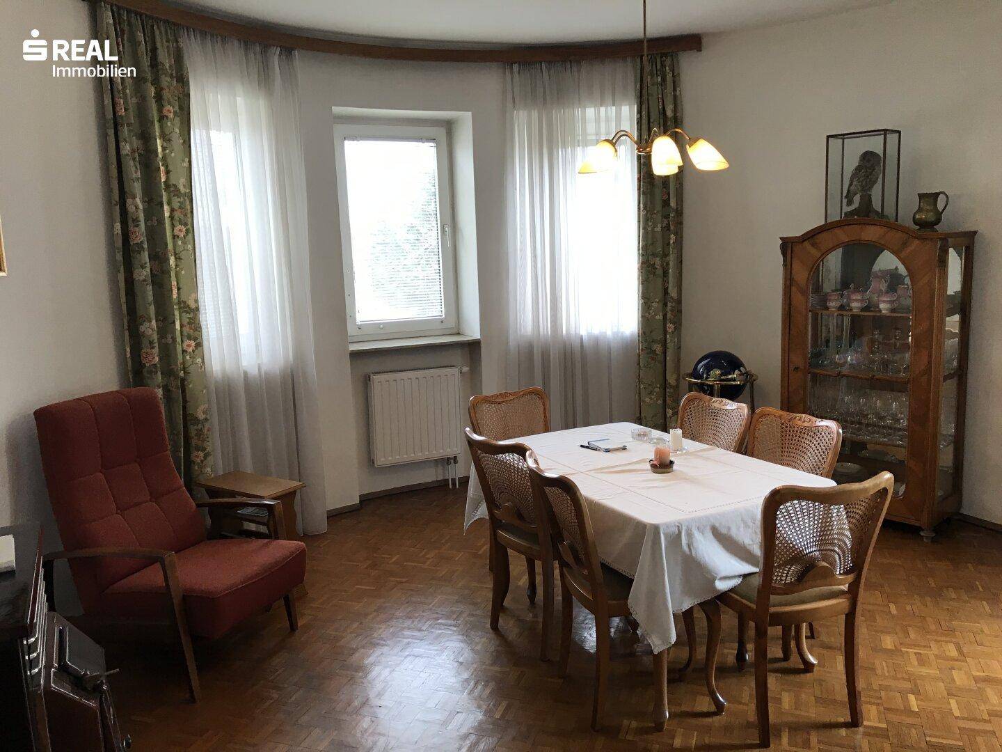 Klassisches Esszimmer mit Fischgrätparkett, großem Esstisch und traditionellen Möbeln.