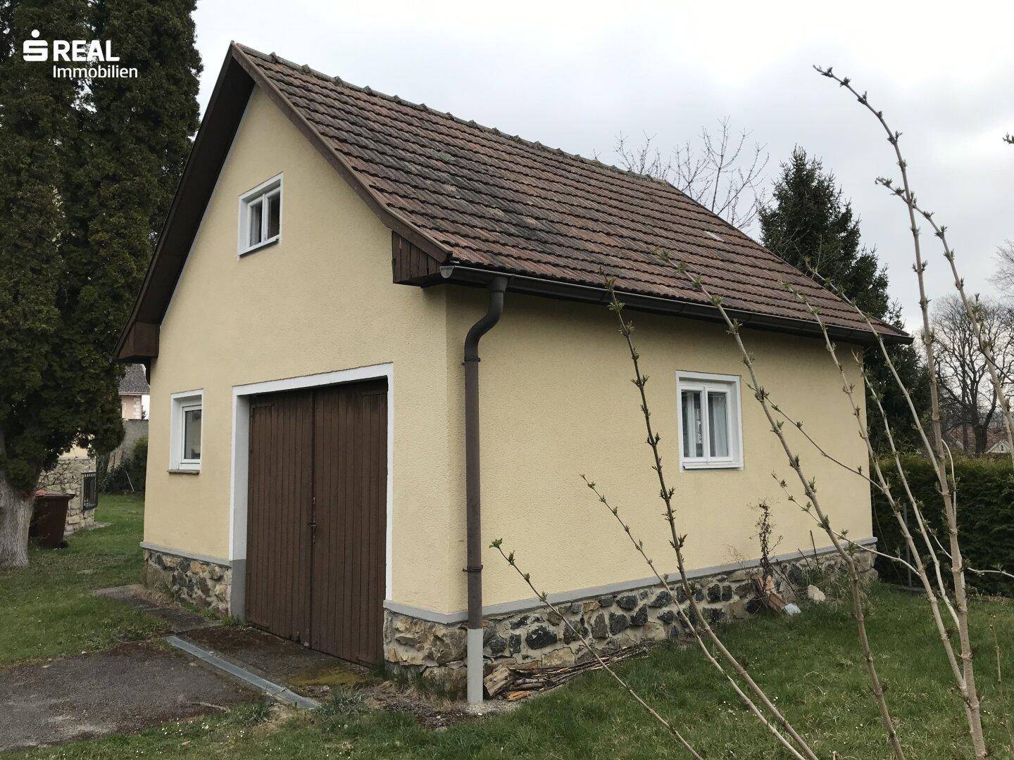 Freistehende Garage oder Nebengebäude mit Satteldach und Holztoren.