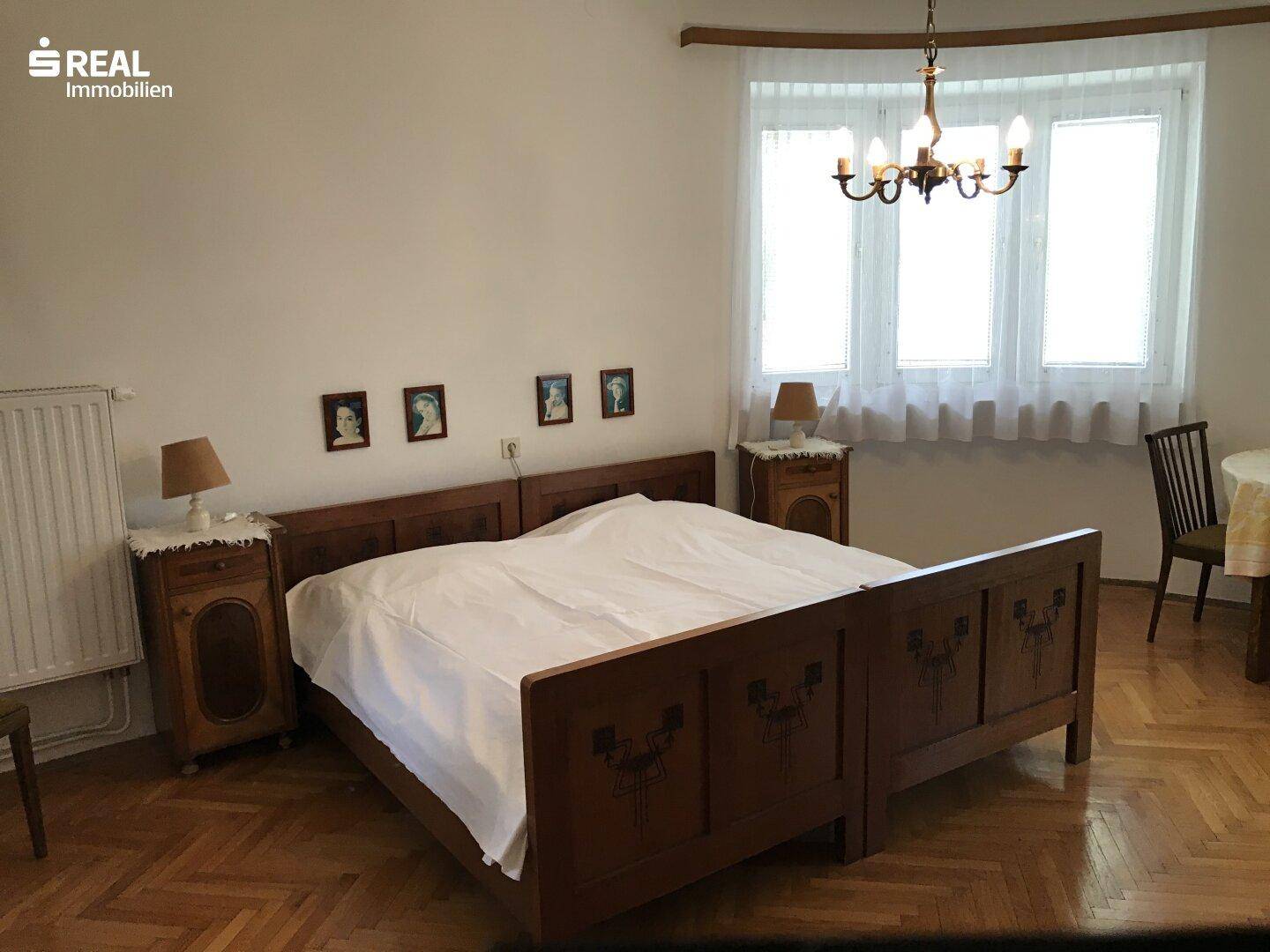 Schlafzimmer mit Doppelbett, Nachttischen und Parkettboden.