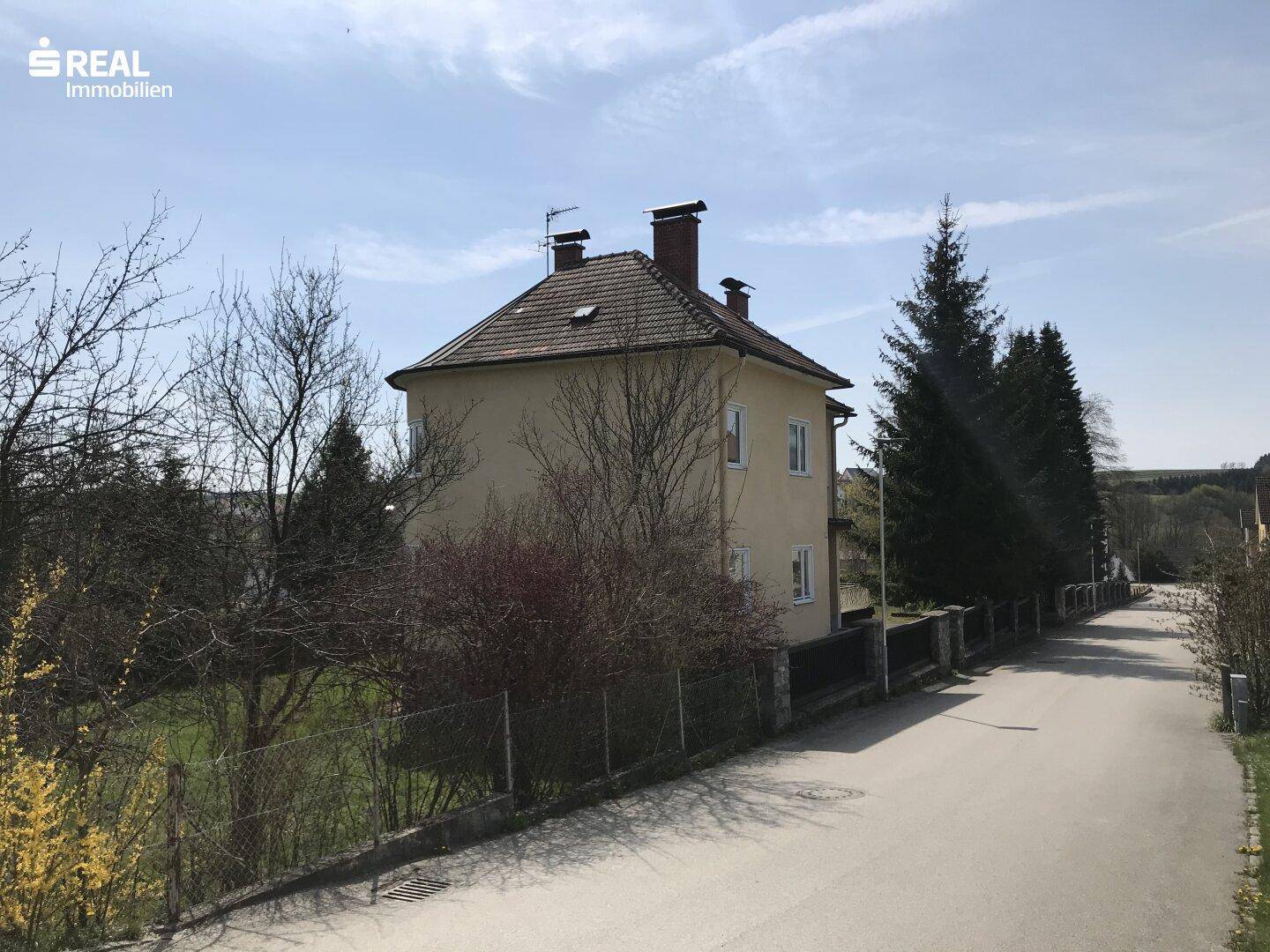 Hausansicht von der Straße aus, umgeben von Bäumen und ländlicher Umgebung.