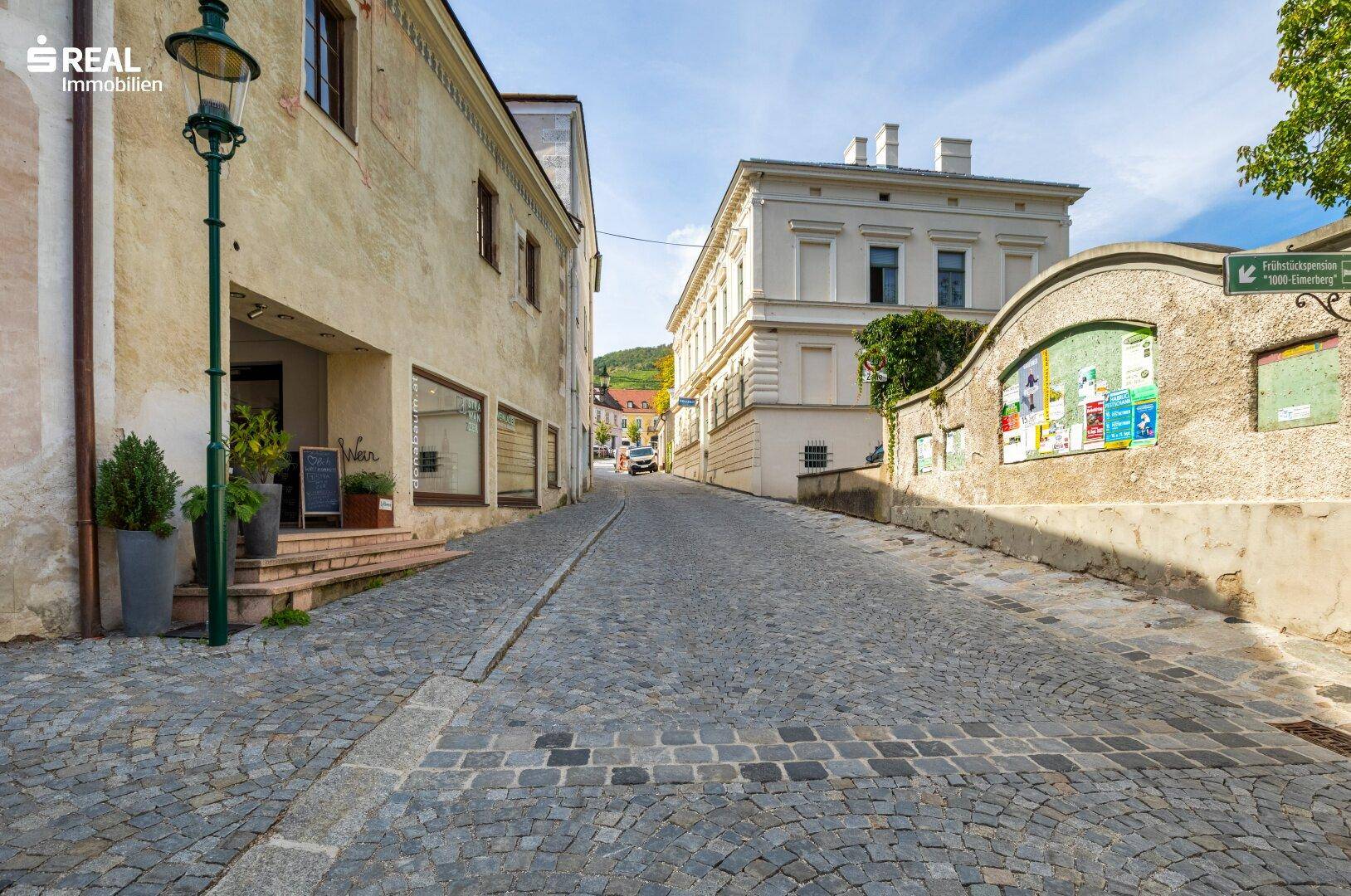 Historische Gasse mit Kopfsteinpflaster, alten Gebäuden und einer traditionellen Straßenlaterne.